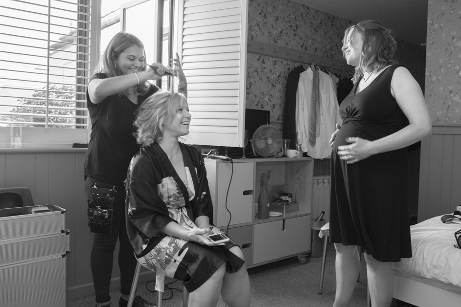 bride laughs and chats to pregnant bridesmaid while having her hair styled at Brooks Guesthouse in Bristol