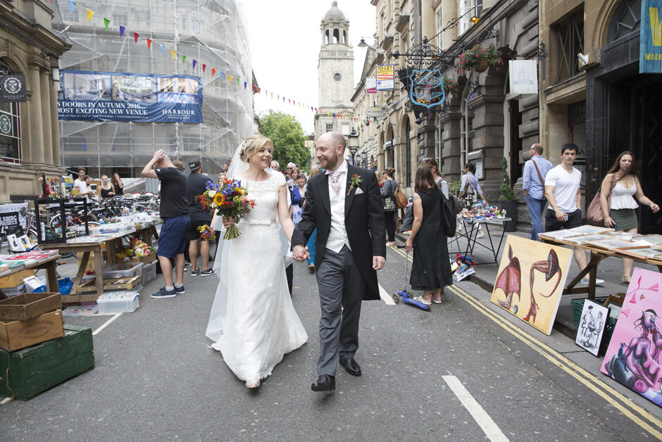 bride and groom walking through Bristol highstreet during market after getting married