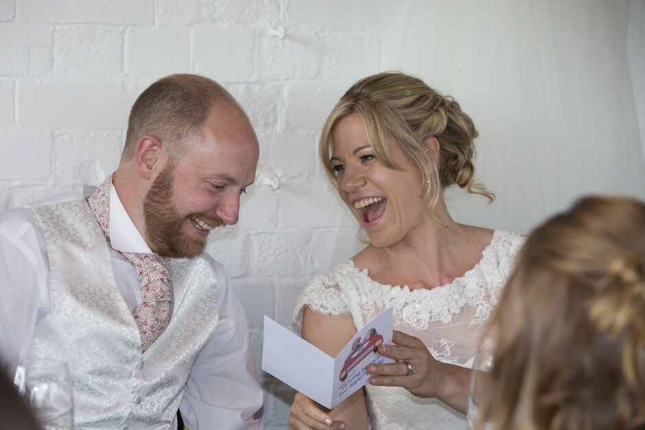 bride and groom laughing over a card received during the wedding speeches at The Ethicurean in Bristol