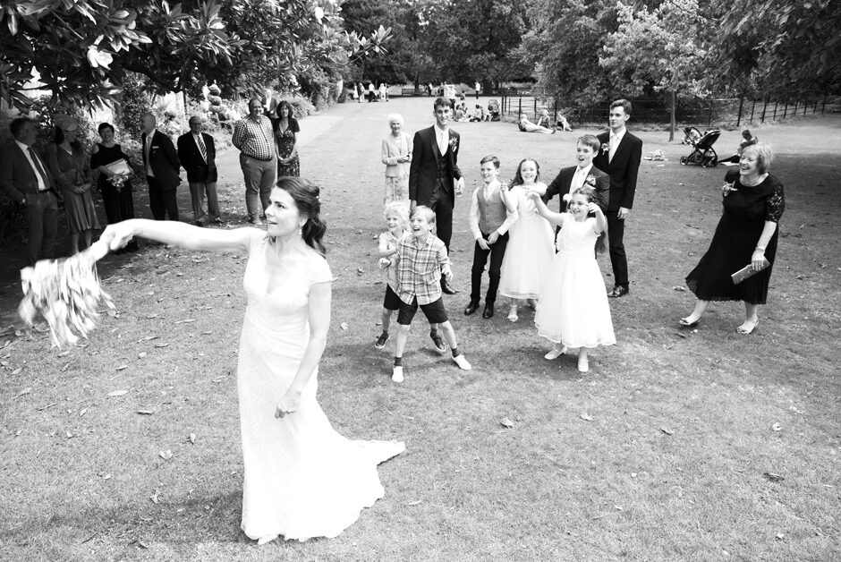 bride throwing the wedding bouquet to children at Lewes Register gardens