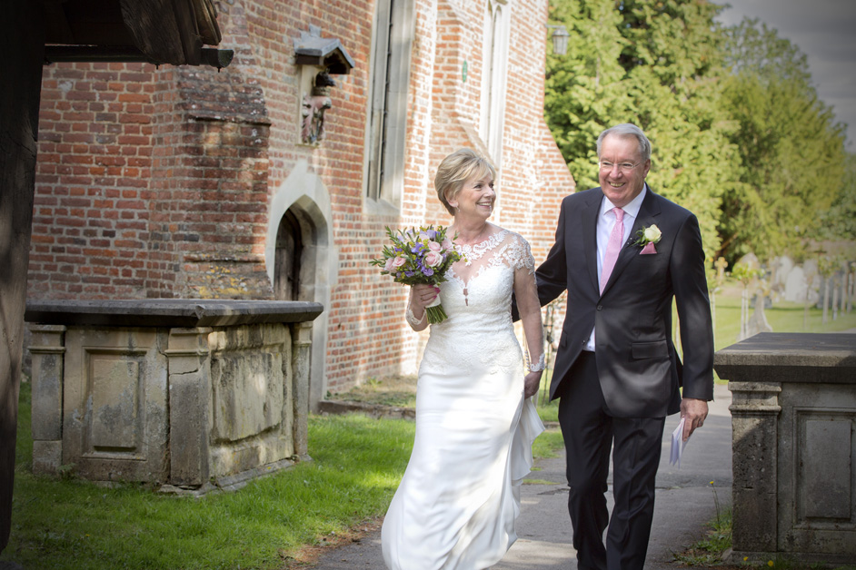 bride and groom walking into entrance of Stoke Poges Church for wedding ceremony in Reading