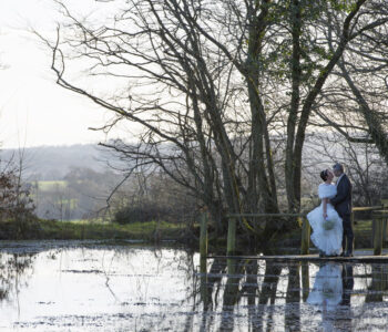 bride and groom sharing loving embrace by lake at Swallows Oast in Tunbridge Wells