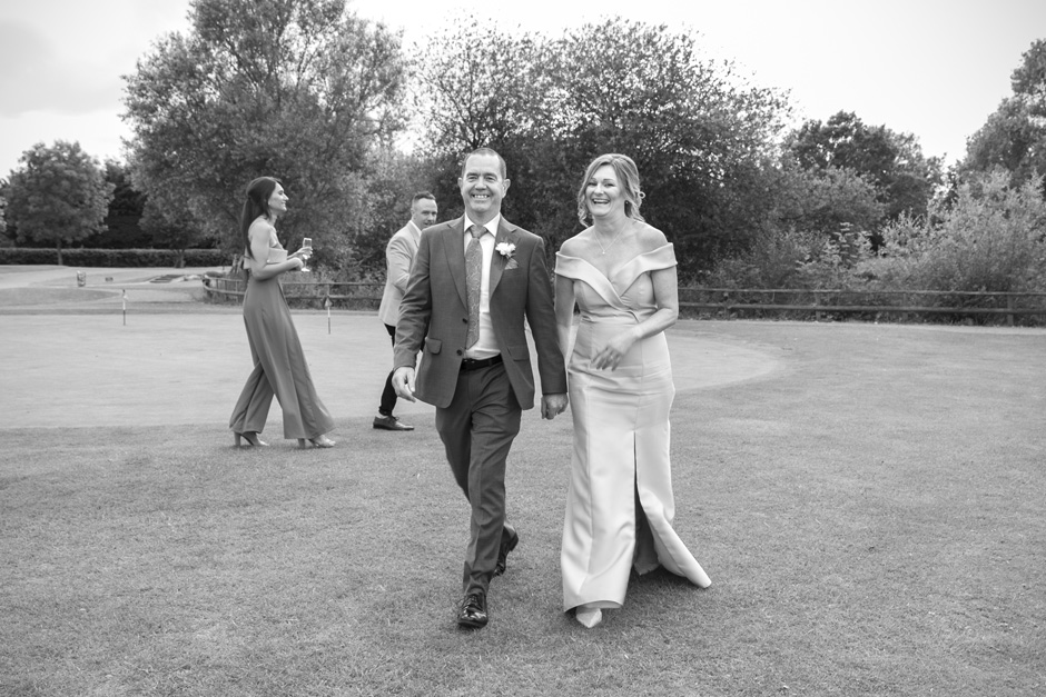bride and groom walking across the golf course at their Weald of Kent wedding in Kent
