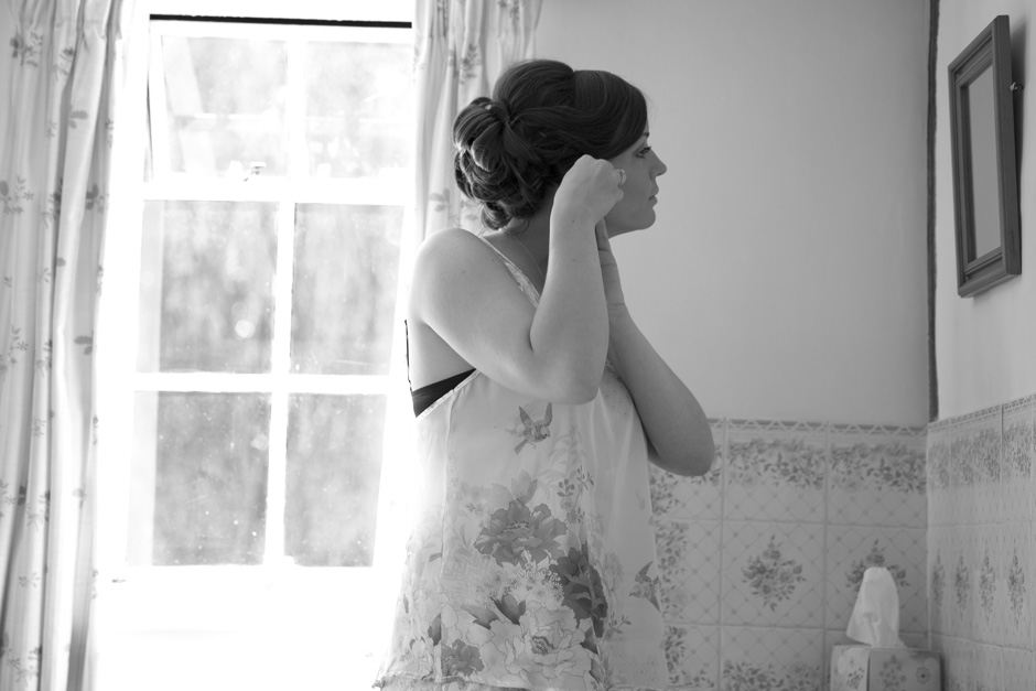 bride putting on earrings looking in the mirror at her Smarden home wedding in Kent