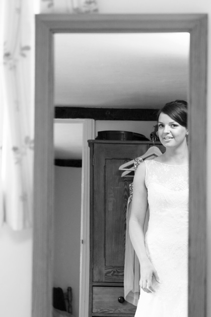 bride looking in mirror at her dress during bridal prep at Smarden village home in Kent