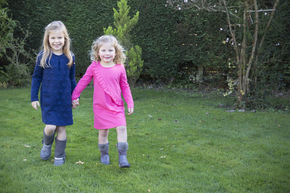 little girls holding hands walking in their garden in West Malling, Kent