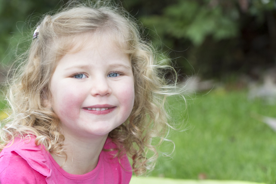 close-up of little girl with blonde curly hair in West malling garden in Kent