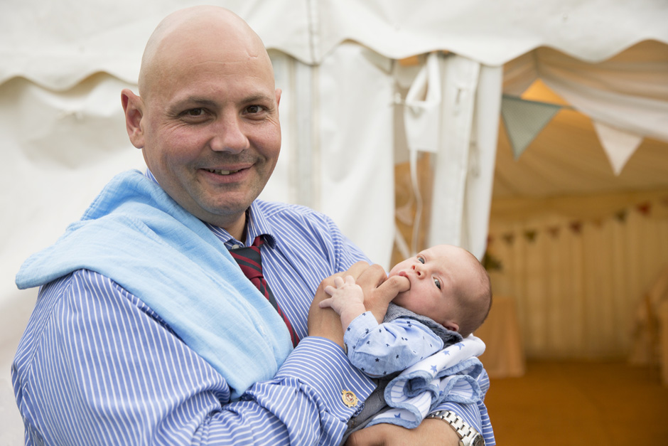 father cradling baby at Smarden village home marquee wedding in Kent