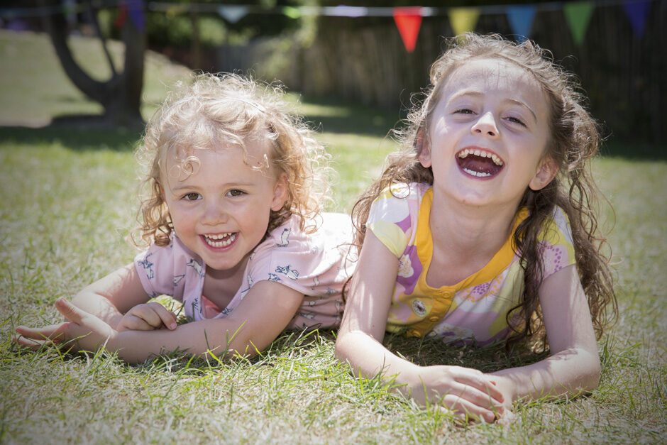 little sisters laughing together at summer fete in Tonbridge, Kent