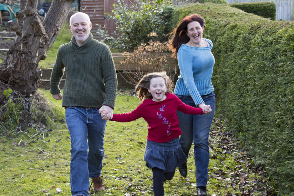 little girl running with her smiling parents in her garden in Tonbridge, Kent