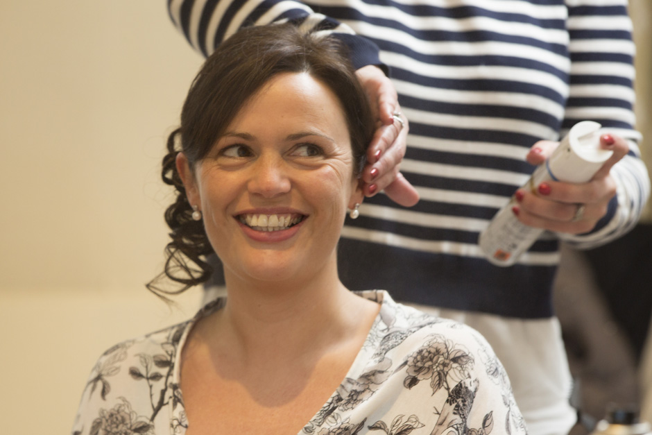 bride smiling while having her hair sprayed during bridal prep at Dale Hill Hotel in Ticehurst, East Sussex