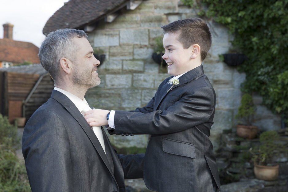 best man son helping his dad with his tie outside Swallows Oast in Ticehurst, East Sussex