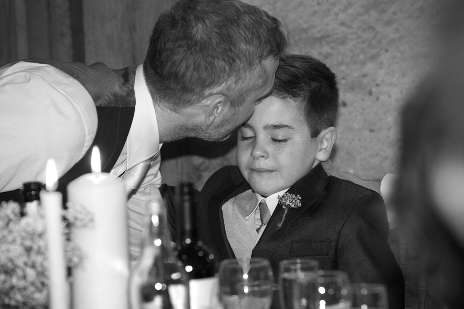 groom kissing little boy best man during wedding speeches at Swallows Oast in Ticehurst, East Sussex