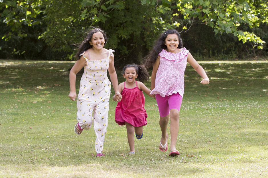 Three little sisters running holding hands captured by Kent family photographer Victoria Green