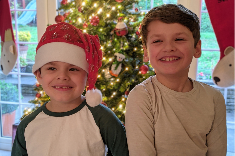 two little boys standing by the christmas tree laughing