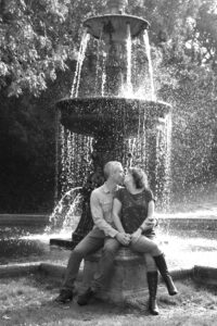 Engagement shoot with couple sitting by water fountain at Dunorlan Park, Tunbridge Wells in Kent