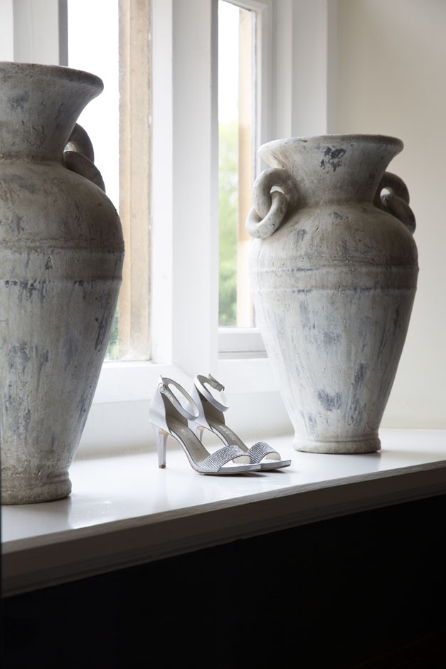 bride's shoes taken on shelf next to large ceramic pots at Wotton House in Dorking, Surrey