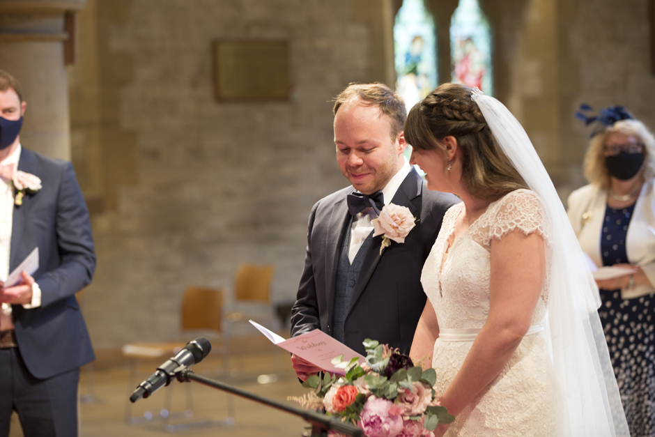 Groom and bride laughing reading order of service at St Stephen's Church wedding in Tonbridge, Kent