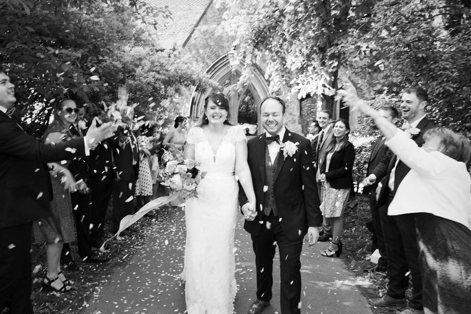 Bride and Groom laughing walking through confetti tunnel outside St Stephen's Church in Tonbridge, Kent