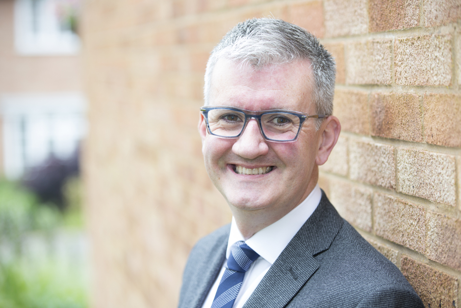 Business man profile head portrait against blurry brick background captured by Kent photographer Victoria Green