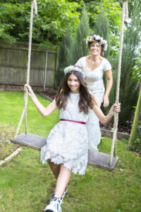 Bridesmaid on swing and bride pushing the swing laughing captured by Kent wedding photographer Victoria Green