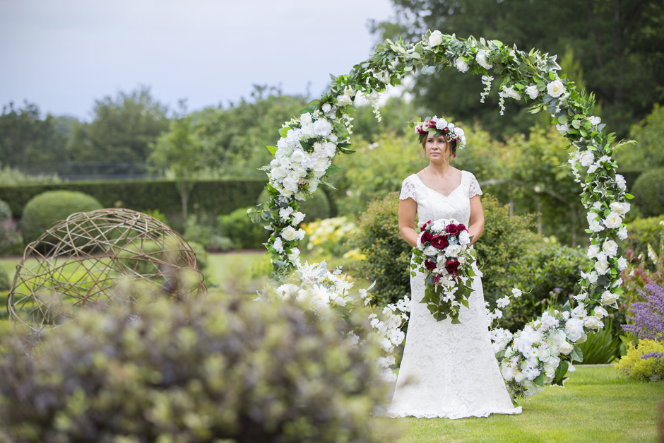 Silk flower moongate (by Lily & Rose) with bride standing in the middle captured by Kent wedding photographer Victoria Green