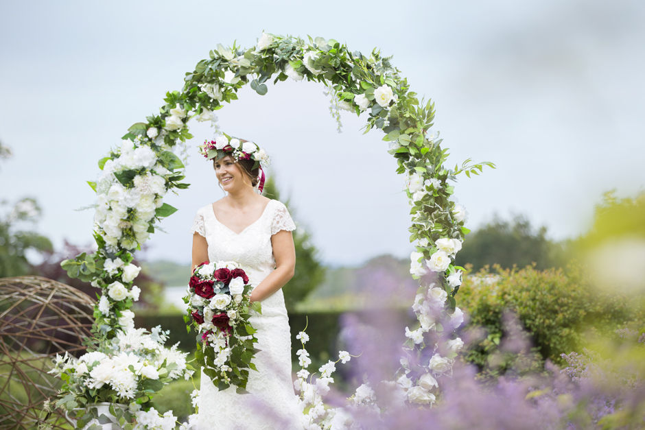 Bride laughing standing in the middle of silk flower moongate (by Heather at Lily & Rose) captured by Tonbridge wedding photographer Victoria Green