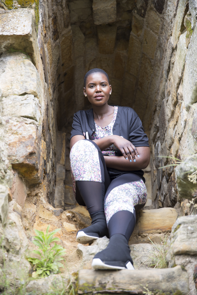Black woman portrait sitting at top of rocks captured by Kent photographer Victoria Green