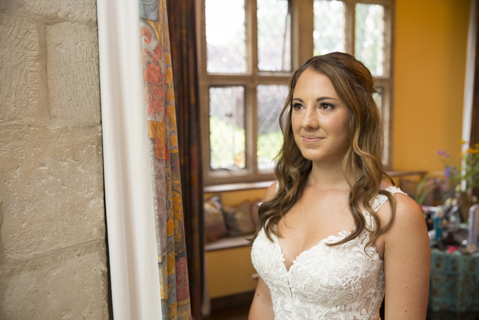 Bride looking thoughtfully outside of window in the bridal suite at Nettlestead Place. Captured by Kent wedding photographer Victoria Green.