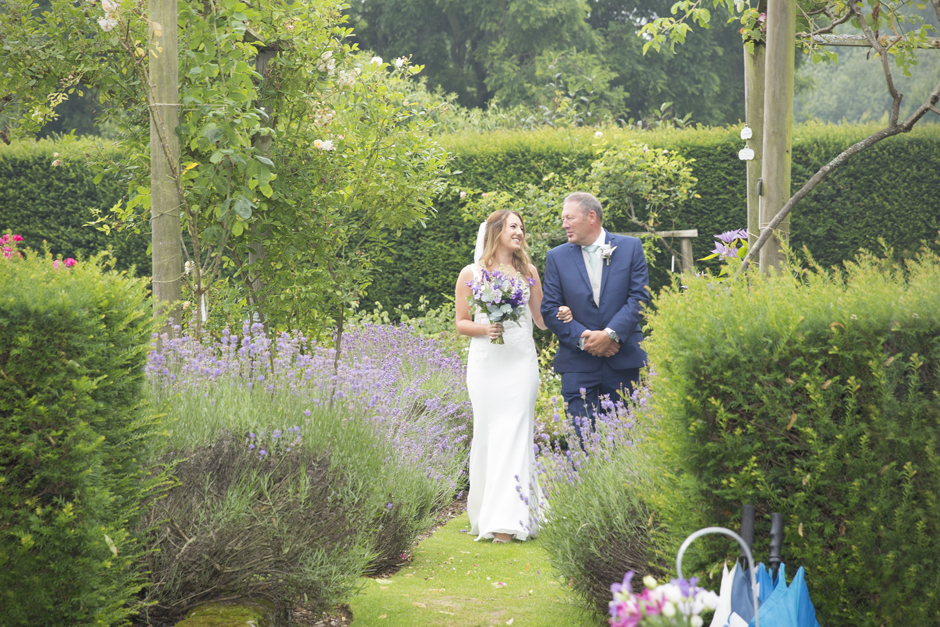 Bride and bride's dad walking down the aisle at outside wedding ceremony at Nettlestead Place. Captured by Kent wedding photographer, Victoria Green.