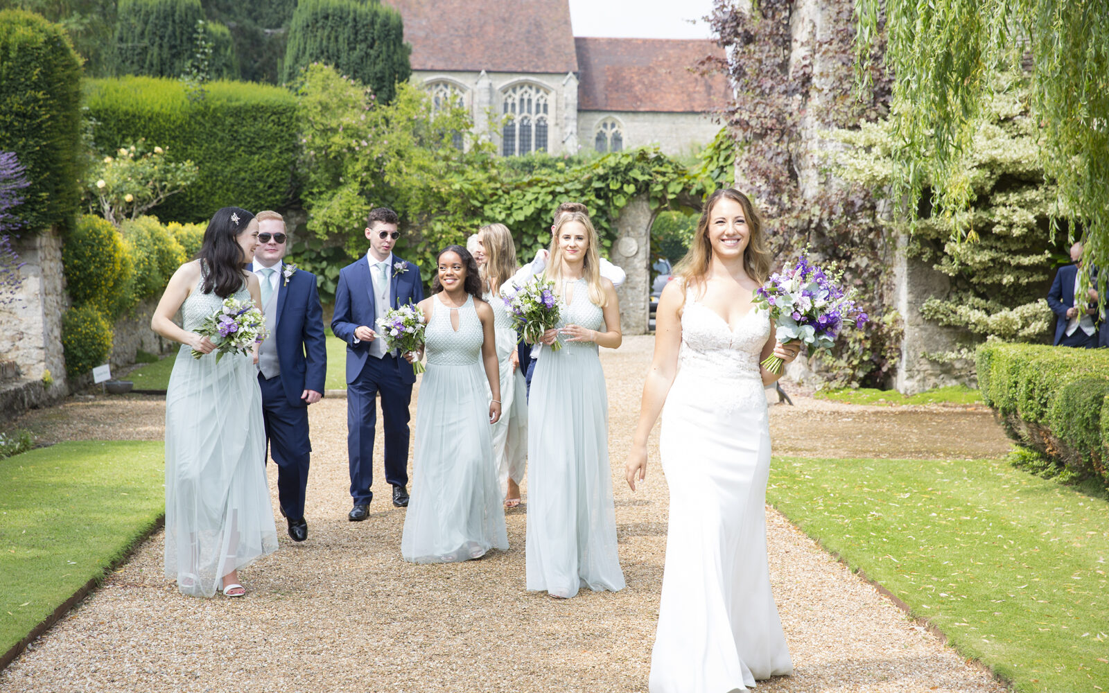 bride with bridal party walking around the grounds at Nettlestead Park in Maidstone. Captured by Kent wedding photographer, Victoria Green.