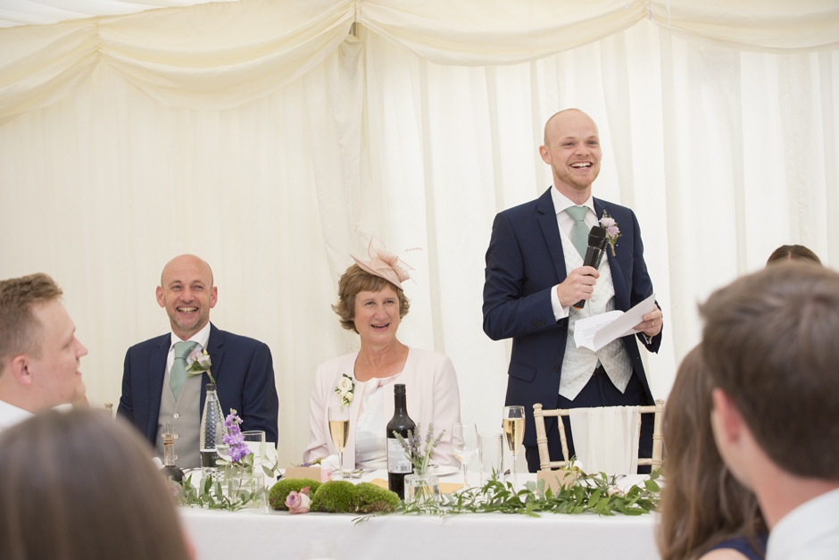 Groom saying speech while parents laugh to his side - captured at Nettlestead Place in Maidstone, Kent.