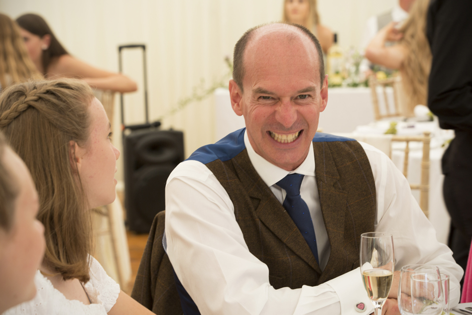 Male wedding guest with very big grin to camera during speeches at Nettlestead Place wedding in Maidstone, Kent.