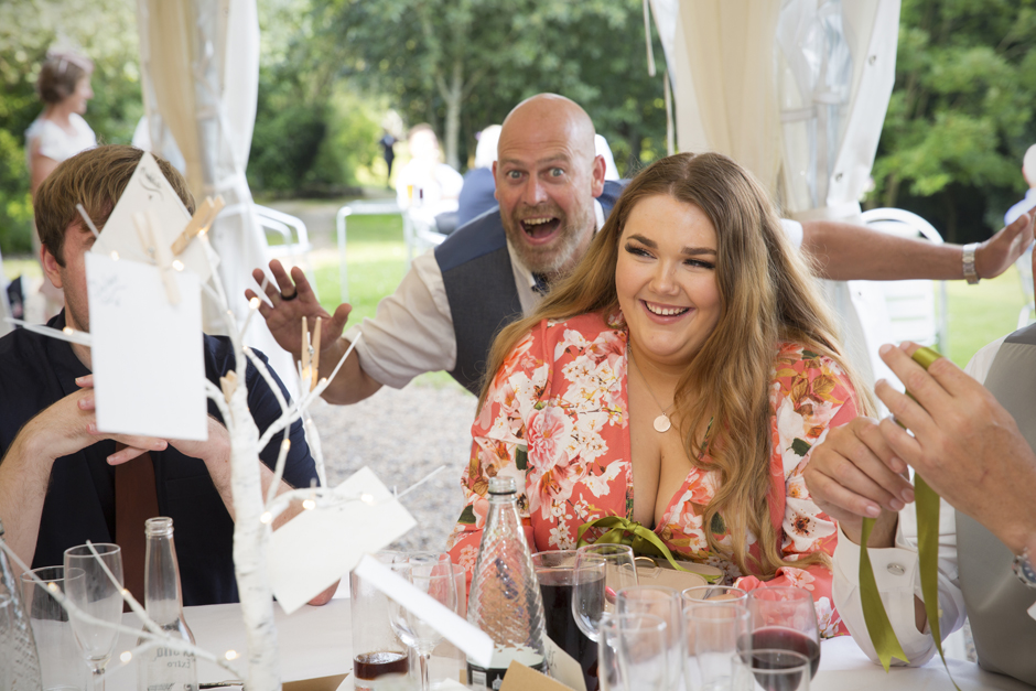 Female wedding guest laughing while being photo bombed from behind at Nettlestead Place, in Kent.