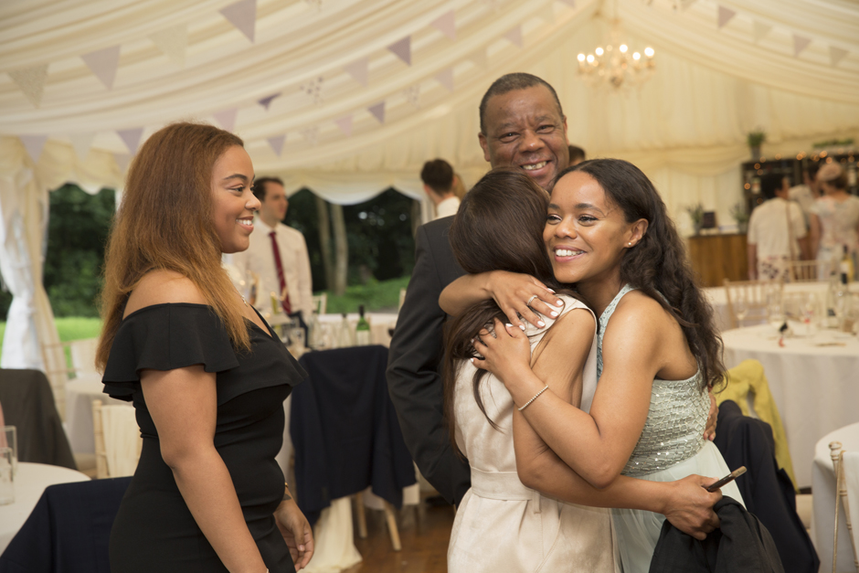 Evening wedding guests hug bridesmaid at reception at Nettlestead Place, Kent.