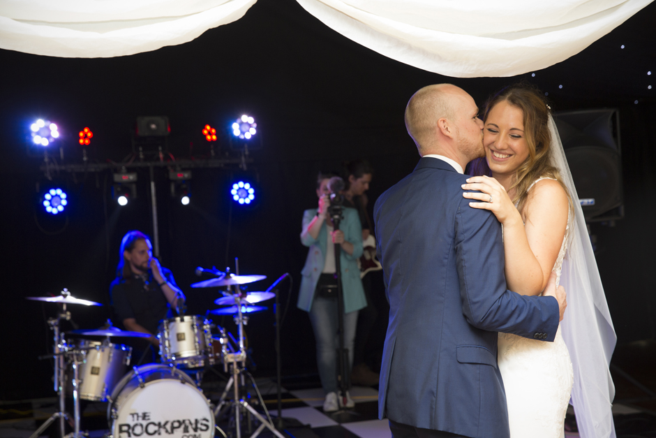 Bride and groom first dance with bride laughing as groom kisses her. Captured at Nettlestead Place in Kent by Kent wedding photographer Victoria Green.