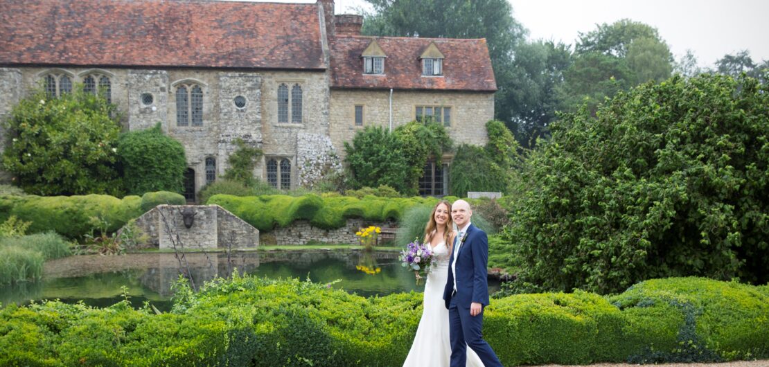 bride and groom walking in front of Nettlestead Place in Kent, captured by Kent wedding photographer Victoria Green