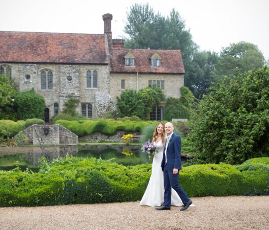 bride and groom walking in front of Nettlestead Place in Kent, captured by Kent wedding photographer Victoria Green
