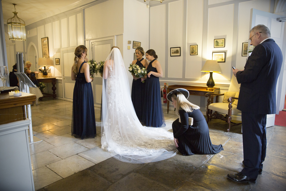 Back of brides dress with mother making adjustments at Bradbourne House wedding in East Malling, Kent.