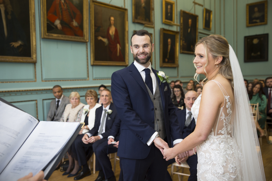 Close-up of bride and groom holding hands smiling during wedding ceremony at Bradbourne House in East Malling in Kent.