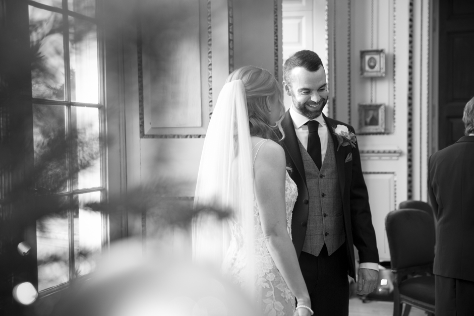 Side shot of groom laughing with bride next to him during wedding ceremony at Bradbourne House in East Malling, Kent.