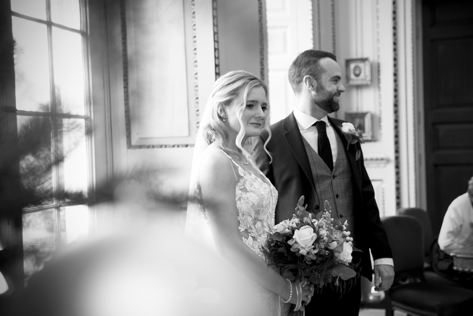 Bride looking thoughtfully standing next to groom at wedding ceremony at Bradbourne House in East Malling, Kent.