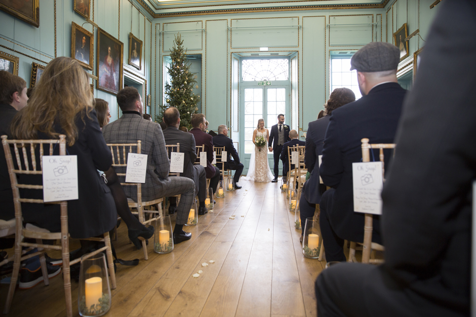 Back of ceremony room with bride and groom standing together holding hands facing their guests at Bradbourne House wedding ceremony at East Malling in Kent.