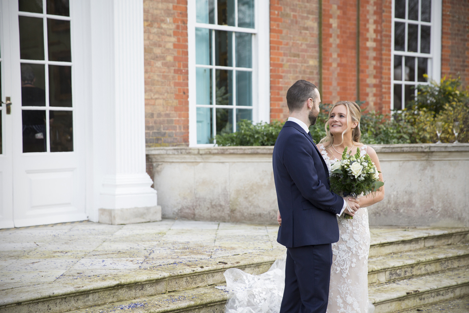 Groom looking at bride holding hands outside Bradbourne House in East Malling in Kent.