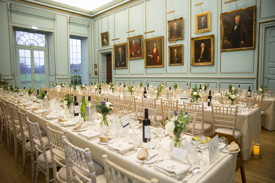 Wedding breakfast tables ready with portraits on wall at Bradbourne House in East Malling, Kent.
