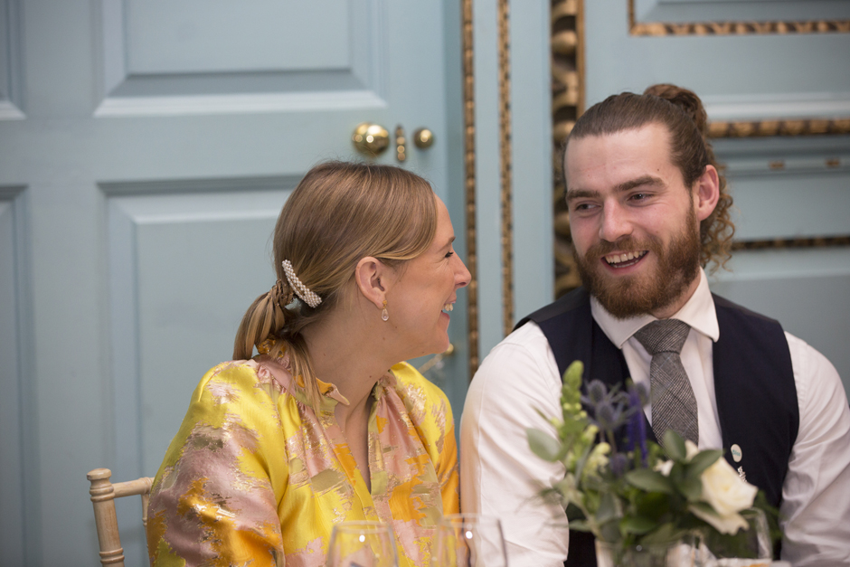 Wedding couple laughing seated during wedding breakfast at Bradbourne House in East Malling, Kent.