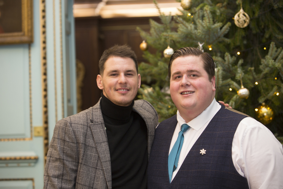 Male wedding guests standing together posing by Christmas tree at Bradbourne House in East Malling, Kent.
