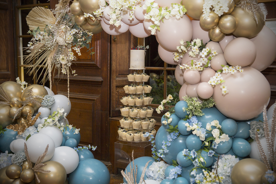 Close up of cupcakes with cake on top tier under balloon arch at Bradbourne House in East Malling, Kent.
