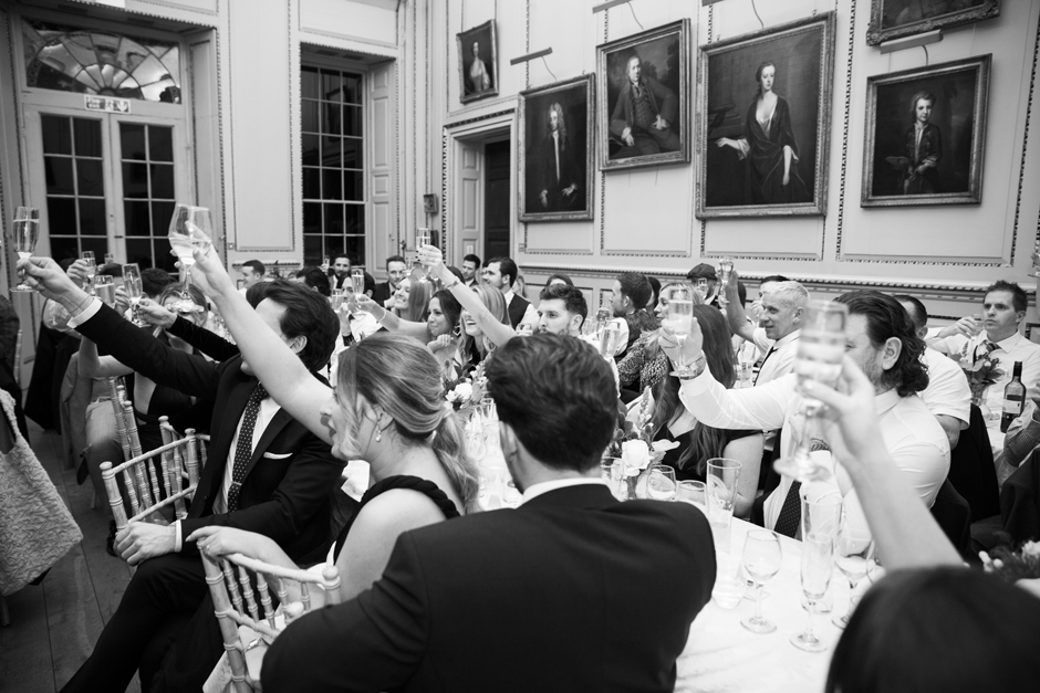 Wedding guests all seated raising their glasses during wedding breakfast at Bradbourne House in East Malling, Kent.