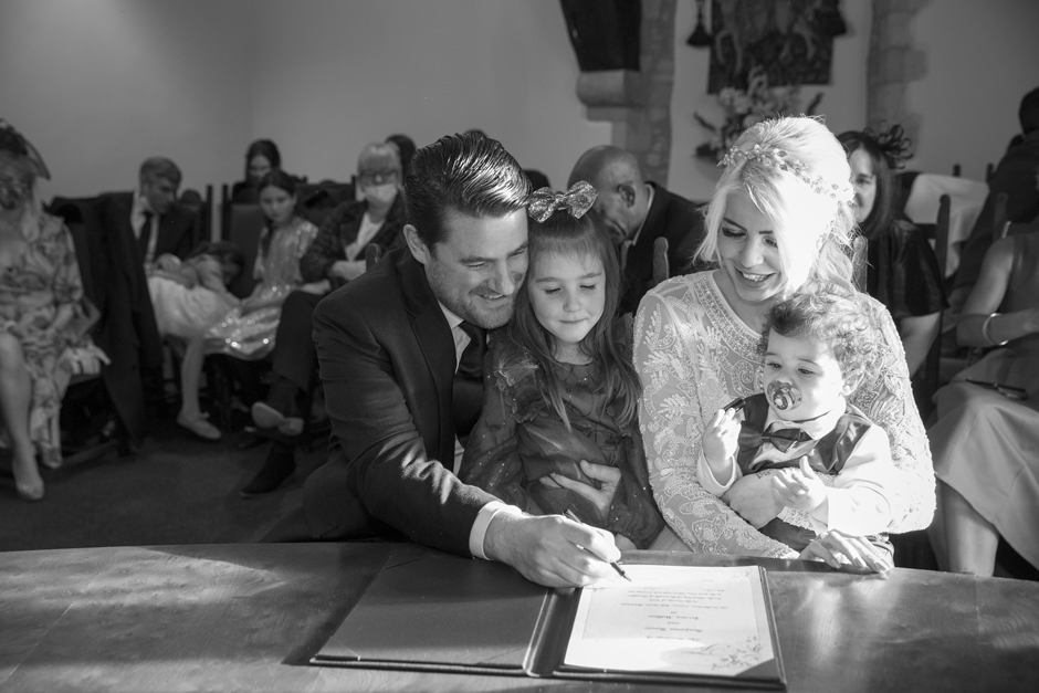 Bride and Groom sitting together signing the register at wedding ceremony in Archbishop's Palace in Maidstone, Kent. Captured by Kent wedding photographer, Victoria Green.
